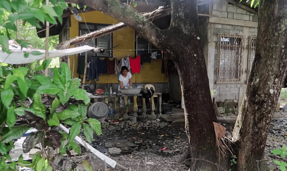 filipino woman washing clothes outside in a typical barangay in the philippines